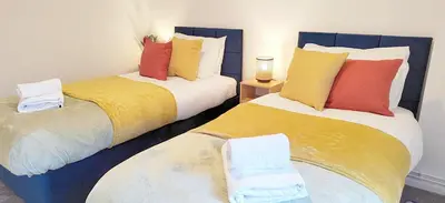 two beds with colorful pillows on them in a room at Modern 2 BR Apartment near Town in Newmarket