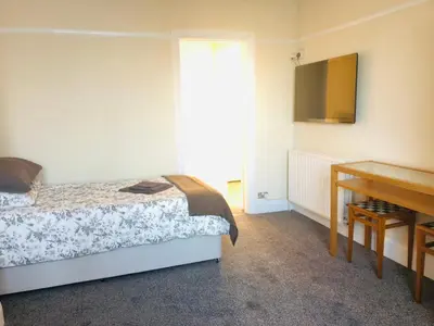 a bedroom with a bed and a desk and a television at AC Lounge 119a in Rochford