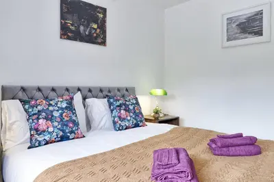 a bedroom with a bed with purple towels on it at Stylish 3 bedroom House In Grt Gregorie Basildon & Essex - Free Wifi, Parking, Dedicated Office & Private Garden in Basildon
