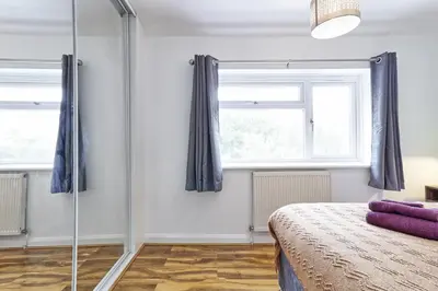 a bedroom with a bed and two windows at Stylish 3 bedroom House In Grt Gregorie Basildon & Essex - Free Wifi, Parking, Dedicated Office & Private Garden in Basildon
