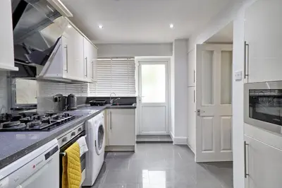 a kitchen with white cabinets and a stove top oven at Stylish 3 bedroom House In Grt Gregorie Basildon & Essex - Free Wifi, Parking, Dedicated Office & Private Garden in Basildon