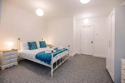 a bedroom with a bed with blue sheets and a night stand at 1 Abbey Mews, Leiston in Leiston