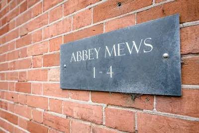 a sign for abbey meys on a brick wall at 1 Abbey Mews, Leiston in Leiston
