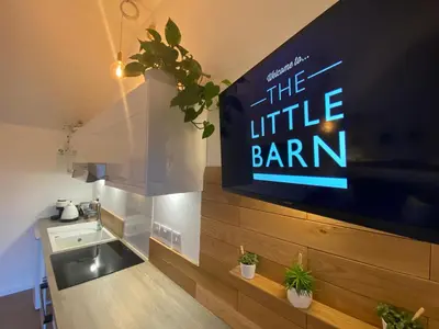 a large tv on a wall in a kitchen at The Little Barn in Hoxne