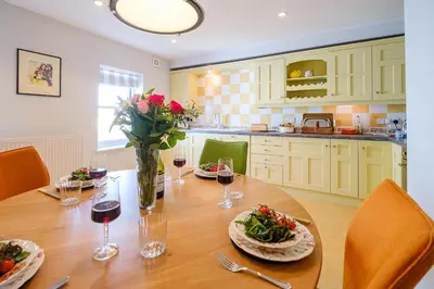 a kitchen with a wooden table with food and wine glasses at Crew Quarters in Aldeburgh