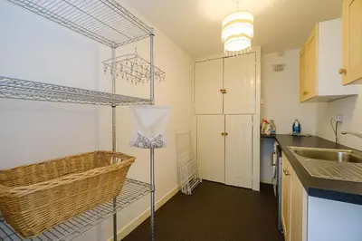 a kitchen with a sink and a shelf with a basket at Frogmore Cottage in Leiston