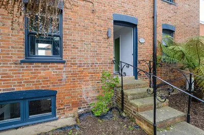 a brick house with stairs leading to a door at Frogmore Cottage in Leiston