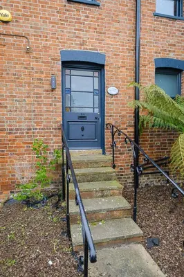 a blue door on a brick building with stairs at Frogmore Cottage in Leiston