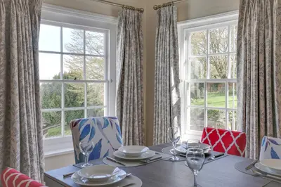 a dining room with a table and two windows at The Red House Maldon in Maldon