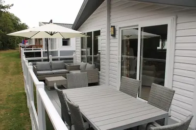 a porch with a table and chairs and an umbrella at Platinum lodge on Carlton Meres holiday Park in Rendham