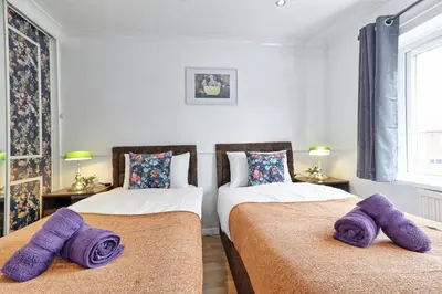two beds in a room with purple towels on them at Elegant 3 Bedroom House in Basildon - Essex Free Parking & Superfast Wifi, upto 6 Guests in Basildon