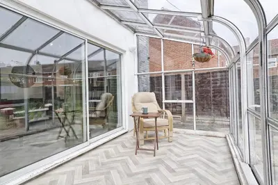 a glass conservatory with a chair and a table at Elegant 3 Bedroom House in Basildon - Essex Free Parking & Superfast Wifi, upto 6 Guests in Basildon