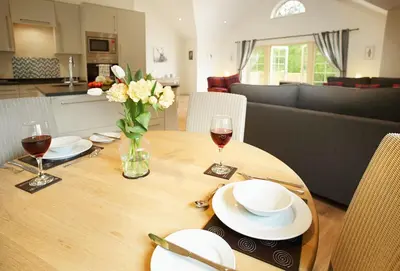 a wooden table with a vase of flowers and wine glasses at Campion Lodge in Chappel