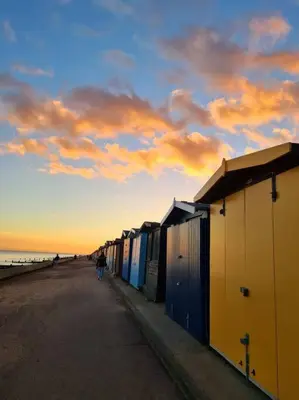a row of beach huts on the beach at sunset at Awave From It All - Escape the city life in Jaywick Sands