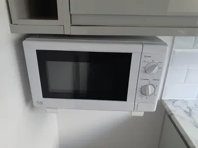 a microwave oven hanging on a wall in a kitchen at Awave From It All - Escape the city life in Jaywick Sands