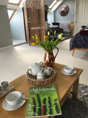 a table with a magazine and a vase with flowers at Willow Barn luxury countryside accommodation in Bury St Edmunds in Bury Saint Edmunds