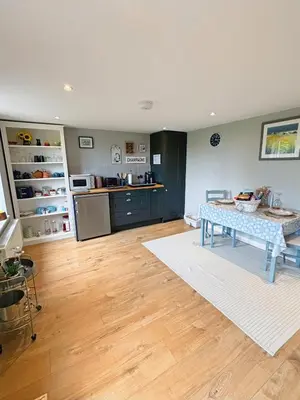 a living room with a table and a kitchen at Willow Barn luxury countryside accommodation in Bury St Edmunds in Bury Saint Edmunds