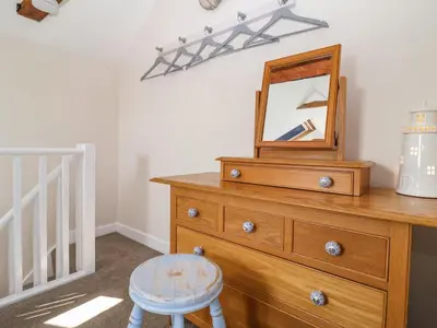 a mirror on top of a dresser with a stool at Admiral Cottage in Woodbridge