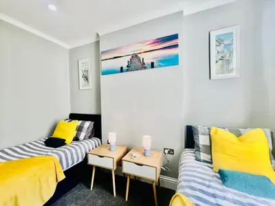 two beds in a room with yellow and blue at Deluxe Apartment in Southend-On-Sea by Artisan Stays I Free Parking I Sleeps 5 in Southend-on-Sea