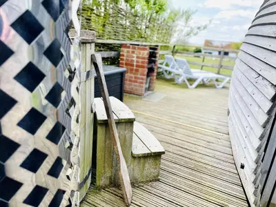 a wooden deck with a bench and a fence at Armadilla 3 at Lee Wick Farm Cottages & Glamping in Clacton-on-Sea