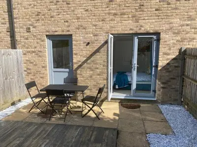 a patio with a table and chairs next to a brick building at Warm & Cosy Homely 4 BDR Chesterton House w High Speed WIFI, Big Garden & Free Parking in Cambridge