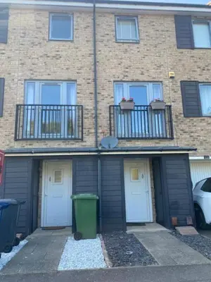 a building with three garage doors and a trash can at Warm & Cosy Homely 4 BDR Chesterton House w High Speed WIFI, Big Garden & Free Parking in Cambridge