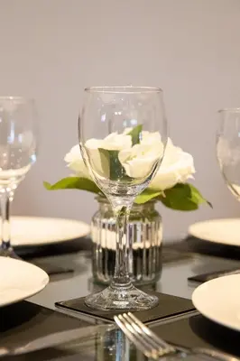 a wine glass on a table with a white rose at Velvet 2-bedroom apartment, Conduit Lane, Hoddesdon in Hoddesdon