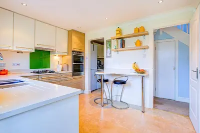 a kitchen with white cabinets and a counter with stools at Serene Family Escape - Spacious, Near Thorpe Bay and Southend, Beaches & Amenities - Pass the Keys in Southend-on-Sea