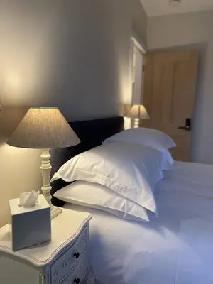 a bed with white pillows and a night stand with a lamp at Moulton Lawn House B&B in Moulton