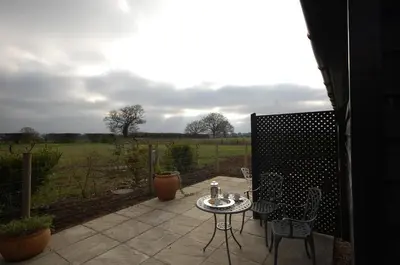 a patio with a table and chairs and a field at The Retreat Field View in Little Maplestead