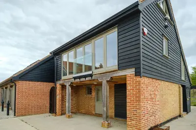 a house with a black roof and glass windows at Alde Bay Farm - Lobster Pot in Aldeburgh