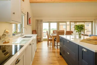 a kitchen with blue cabinets and a dining room at Alde Bay Farm - Lobster Pot in Aldeburgh