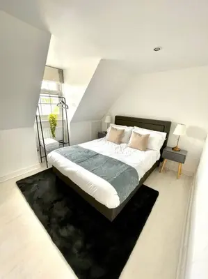 a bedroom with a large bed with a black rug at High-End 2 Bed Maisonette in Beaulieu Park in Broomfield