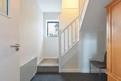 a staircase in a house with a door and a chair at The Lodge Bury St Edmunds in Bury Saint Edmunds