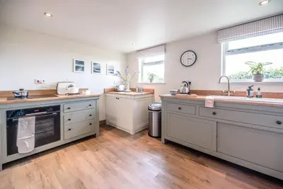 a large kitchen with wooden floors and white cabinets at Gardiners Cottage Barn, Braiseworth in Eye