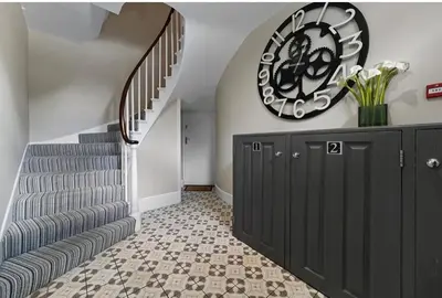 a hallway with stairs and a large clock on the wall at 119 Flat 2 Northgate st - Stylish one bedroom apartment set within walking distance to town, spacious living space with public car park close by in Bury Saint Edmunds
