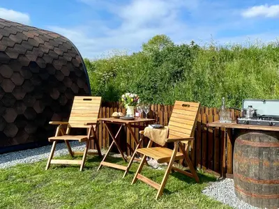two chairs and a table in a yard with a grill at Waterpump Pod for 2 adults with ensuite in the Suffolk Countryside in Badingham