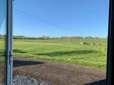 a view of a field through a sliding glass door at Waterpump Pod for 2 adults with ensuite in the Suffolk Countryside in Badingham