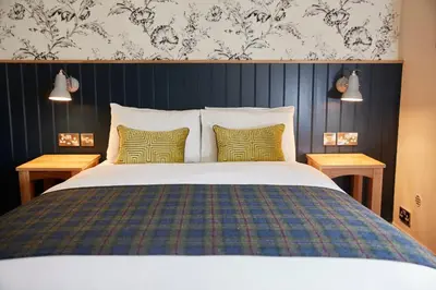 a bedroom with a large bed with two tables at Swan Hotel by Greene King Inns in Thaxted