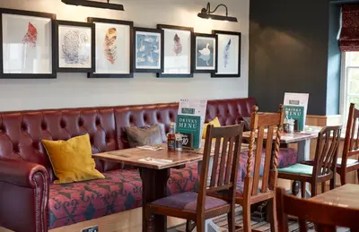 a restaurant with tables and chairs and a bench at Swan Hotel by Greene King Inns in Thaxted