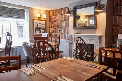 a restaurant with tables and chairs and a fireplace at Swan Hotel by Greene King Inns in Thaxted