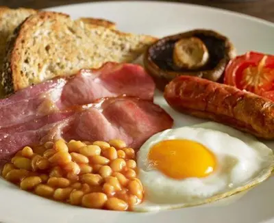 a plate of breakfast food with eggs bacon beans and toast at Swan Hotel by Greene King Inns in Thaxted