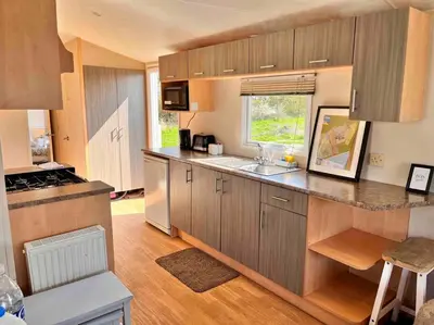 a kitchen with wooden cabinets and a counter top at Lola’s Caravan. Your home away from home. in Parkeston