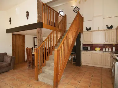 a wooden staircase in a living room with a kitchen at St Andrews Barn in Necton
