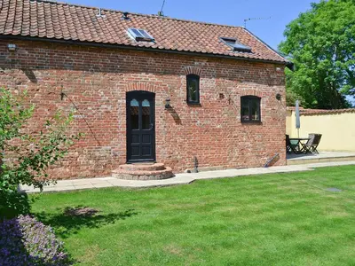 a brick house with a black door and a yard at The Cottage in Great Ellingham