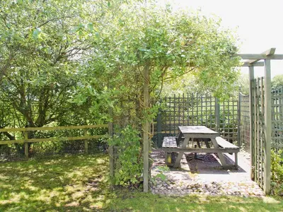 a picnic table under an apple tree next to a fence at The Old House in Mellis