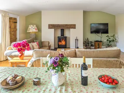 a living room with a table with a bottle of wine at Dove Cottage in Halesworth
