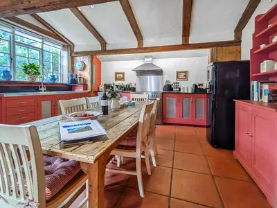 a kitchen with a wooden table and red cabinets at Stable End in Halesworth