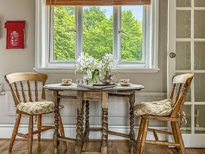 a table with two chairs and a vase of flowers at Nightingales in Hollesley