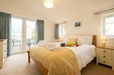 a bedroom with a bed with a table and windows at Annie's House in Thorpeness